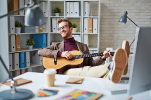 Handsome businessman with guitar singing in office