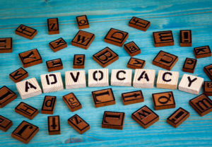 advocacy word written on wood block. Wooden alphabet on a blue background.